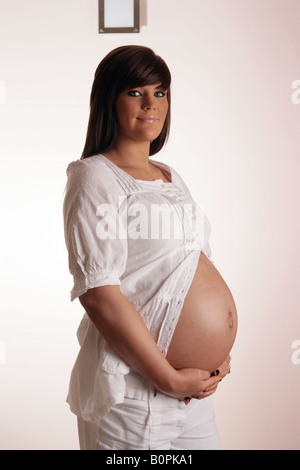 36 week pregnant teenage woman holding her exposed stomach Stock Photo