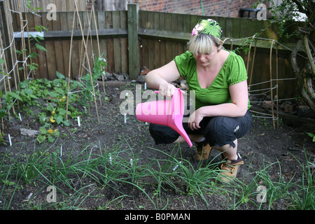 Female woman gardening watering vegetable patch in the back garden Stock Photo