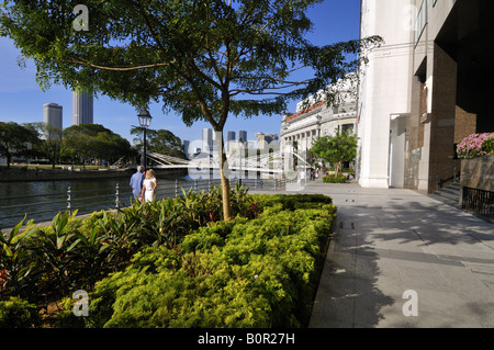 A Caucasian couple walking down Boat Quay by Singapore river towards Fullerton Hotel. Stock Photo