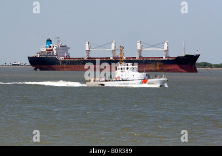 Bulk cargo ship and U S Coast Guard patrol boat in Galveston Bay Texas Stock Photo