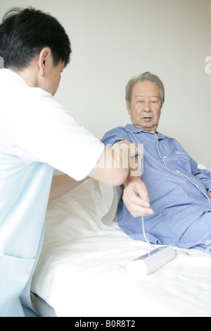 Male nurse taking senior man's blood pressure Stock Photo