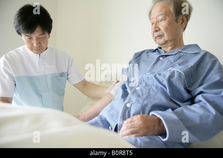 Male nurse taking senior man's blood pressure Stock Photo