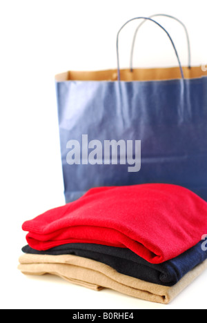 Folded sweaters with a paper shopping bag on white background Stock Photo