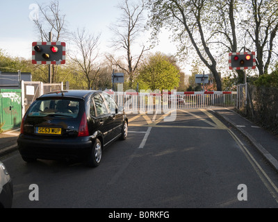 Car waits at a railway level crossing barrier for a train to pass through the crossing. Stock Photo