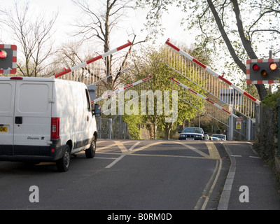 Railway level crossing barrier arms being raised to allow the traffic to flow. Stock Photo