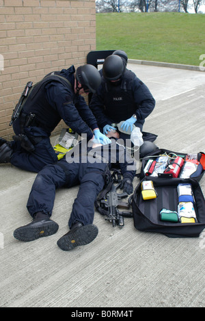 Police firearms officers giving medical assistance to injured officer Stock Photo