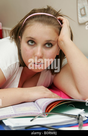 Teenage girl studying for her exams or doing homework looking very exhausted and fed up Stock Photo