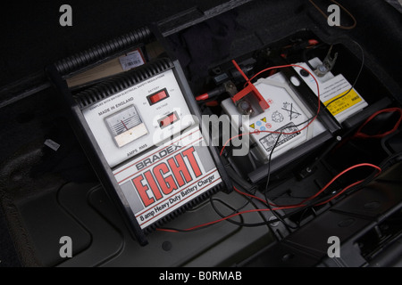Car battery charger charges a flat 12v car battery in a BMW Z4 car Stock Photo