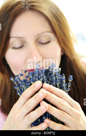 Mature woman smelling lavender flowers focus on hands Stock Photo