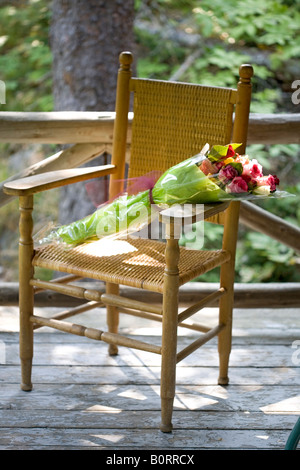 wicker chair on porch with bouquet of flowers Stock Photo