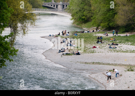 People siting on the banks of the Isar River in the city of Munich capital of  Bavaria. Germany Stock Photo