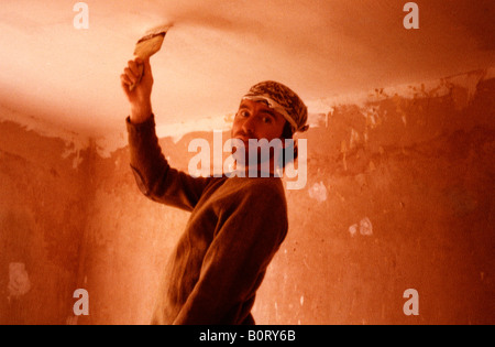 DIY guy man painting a ceiling wearing head scarf Stock Photo