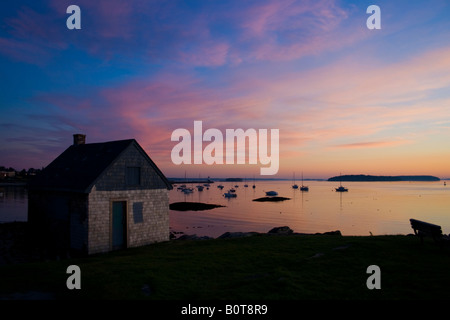 An abandoned lobster shack on the extremity of a rocky outcrop in Maine during the sunrise. Stock Photo