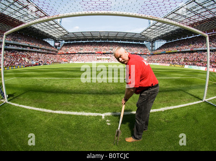 groundkeeper prepares pitch inside empty goal in filled football Stadium before kick-off Stock Photo