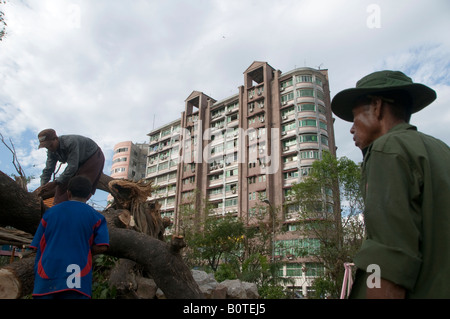 Myanmar sodier surveys workers cleaning up fallen trees and debris caused by Cyclone Nargis in Yangon. May 11, 2008. Stock Photo