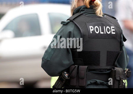 blonde female PSNI police service northern ireland officer on patrol wearing stab proof vest and carrying sidearm