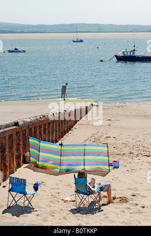 SUNBATHER WITH BOATS IN THE BACKGROUND IN THE SEASIDE TOWN OF ABERDOVEY GWYNEDD WALES Stock Photo