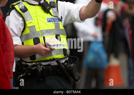 PSNI police service northern ireland policeman officer in high vis jacket with notebook gives pedestrian directions Stock Photo