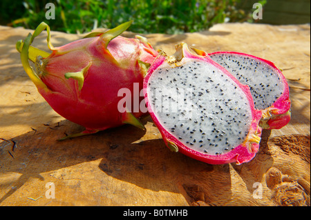 Close up of fresh whole and cut  pitaya, pitahaya or dragon fruit in a table setting outdoors Stock Photo