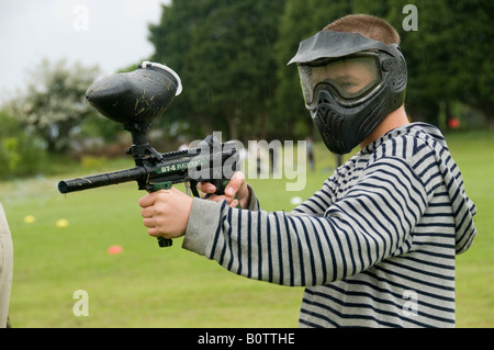 Boy shooting with paint ball gun wearing full face mask protection Stock Photo