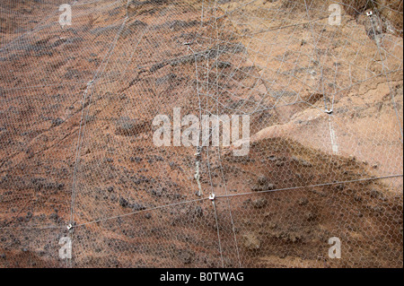 mesh wire cage attached to rocky cliff face to stop rocks falling onto people Tenerife Canary Islands Spain Stock Photo