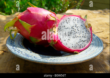 Close up of fresh whole and cut  pitaya, pitahaya or dragon fruit in a table setting outdoors Stock Photo