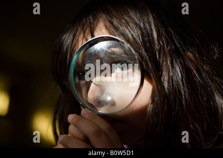 Little girl aged four looks through magnifying glass Stock Photo
