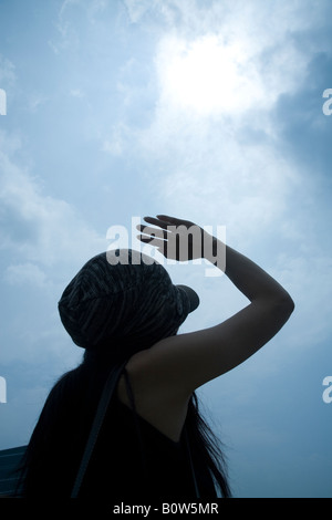 Woman shielding eyes from the sun Stock Photo