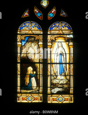 Stained-glass window depicting the Virgin Mary appearing before St. Bernadette, Soubirous, Parish Church of St. Amand Montrond, Stock Photo