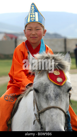 Ten-year-old girl wearing hat with soyombo emblem riding a horse as a participant in the horsemanship competitions of the Naada Stock Photo