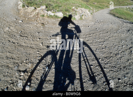 Cyclist's shadow on a gravel road