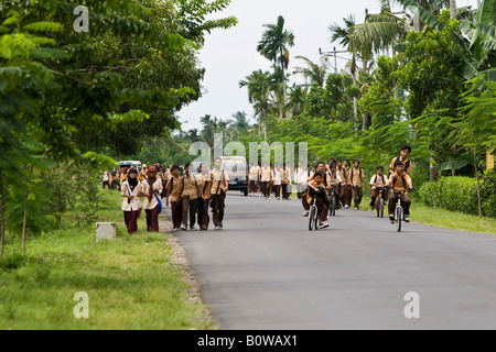 Schoolchildren dressed in uniforms walking along a street after school near Mataram, Lombok Island, Lesser Sunda Islands, Indon Stock Photo