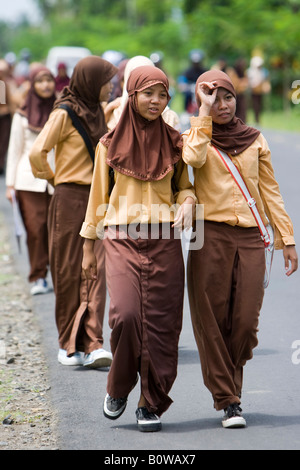 Muslim girls, schoolchildren wearing their uniforms walking along a street after school near Mataram, Lombok Island, Lesser Sun Stock Photo