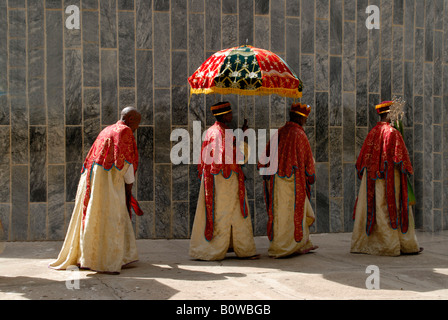 Ethiopian Orthodox procession of priests holding a colourful umbrella walking around the New Cathedral of Axum, Ethiopia, Africa Stock Photo