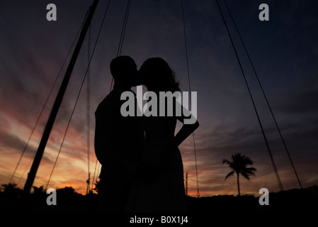 Couple kissing on a boat at sunset. young interracial couple smiling happy Stock Photo