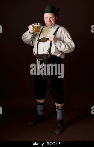 Stereotypical German man in Bavarian costume raising a beer in toast Stock Photo