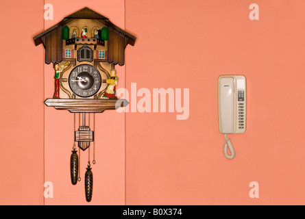 A cuckoo clock and a telephone on a wall Stock Photo