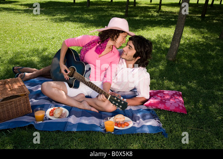 A young couple having a picnic together and playing a guitar Stock Photo