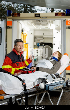 A paramedic assisting a woman in front of an ambulance Stock Photo - Alamy