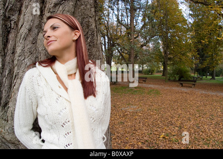 woman in autumn leaning against tree trunk Stock Photo