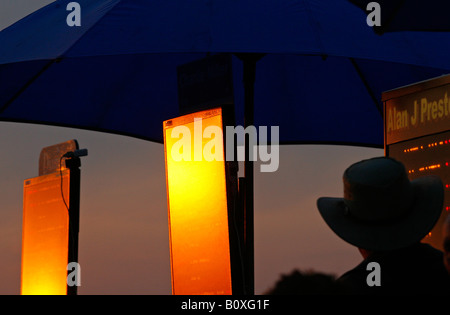 A tote board reflects the last rays of the sun at an evening race meeting at Towcester Racecourse Stock Photo