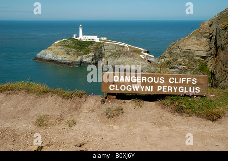 South Stack Lighthouse with sign warning of dangerous cliffs Anglesey North Wales Stock Photo