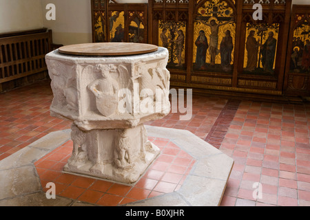 UK England Suffolk Kelsale Arts and Crafts Church of St Peter and Mary interior old carved stone font and septych Stock Photo