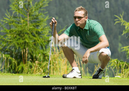 Golf player squatting on golf course Stock Photo