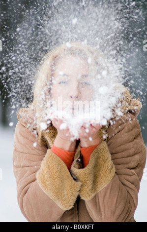 Austria, Salzburger Land, Altenmarkt, Young woman blowing snow off hand, portrait Stock Photo