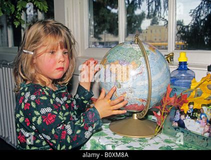 A four year old preschool student examines a globe map of the world at a preschool in Bend Oregon Stock Photo