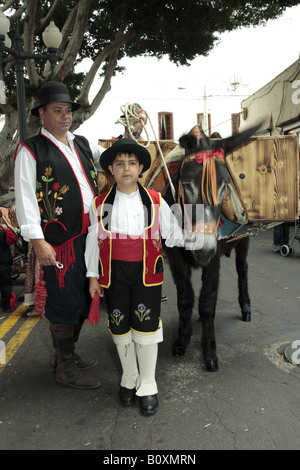 Boy in traditional costume with his father and a donkey at the Romeria de San Isidro in Guia de Isora, Tenerife Stock Photo