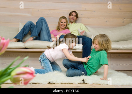 Boy (8-9) and girl (6-7) fighting on carpet, parents in background, portrait Stock Photo