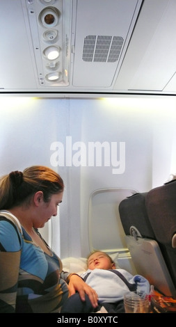 mother in an airplane with her sleeping baby on its lap, Spain, Palma Stock Photo