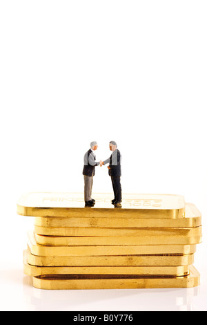 Businessmen figurines standing on stack of gold bars Stock Photo